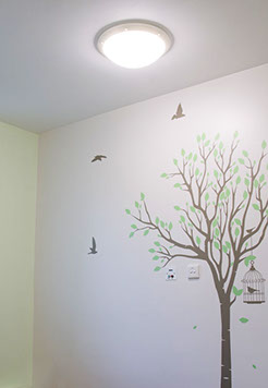 A photo of a light shining on a wall drawing of a tree