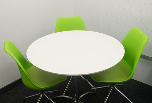 A photo of a small rounb table with three green chairs around it